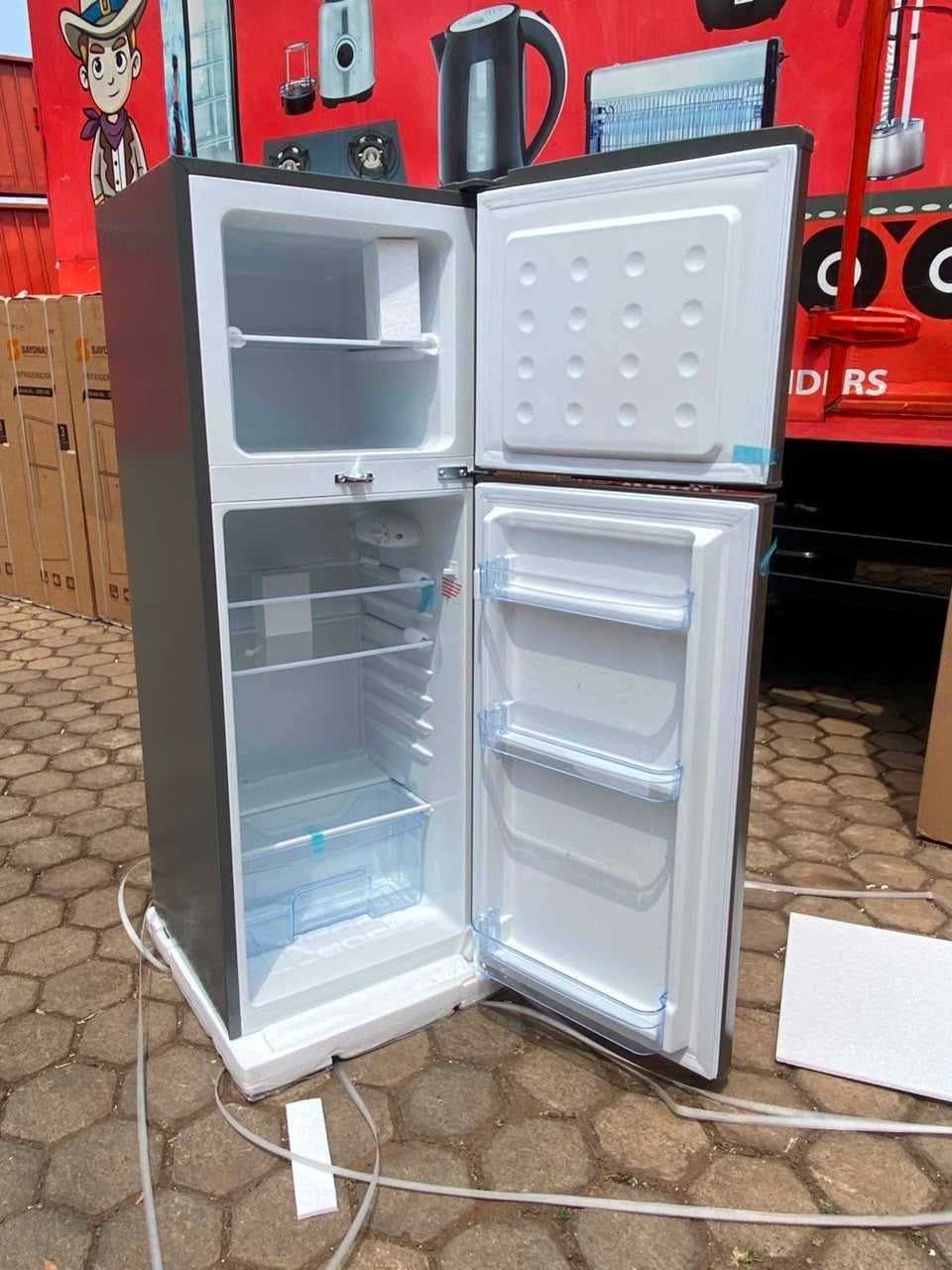 Double-door refrigerator standing open, freezer top bin and lower storage shelves