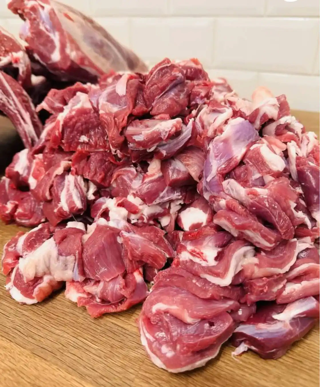 Raw goat meat pieces, red and pink with visible fat, 1kg package