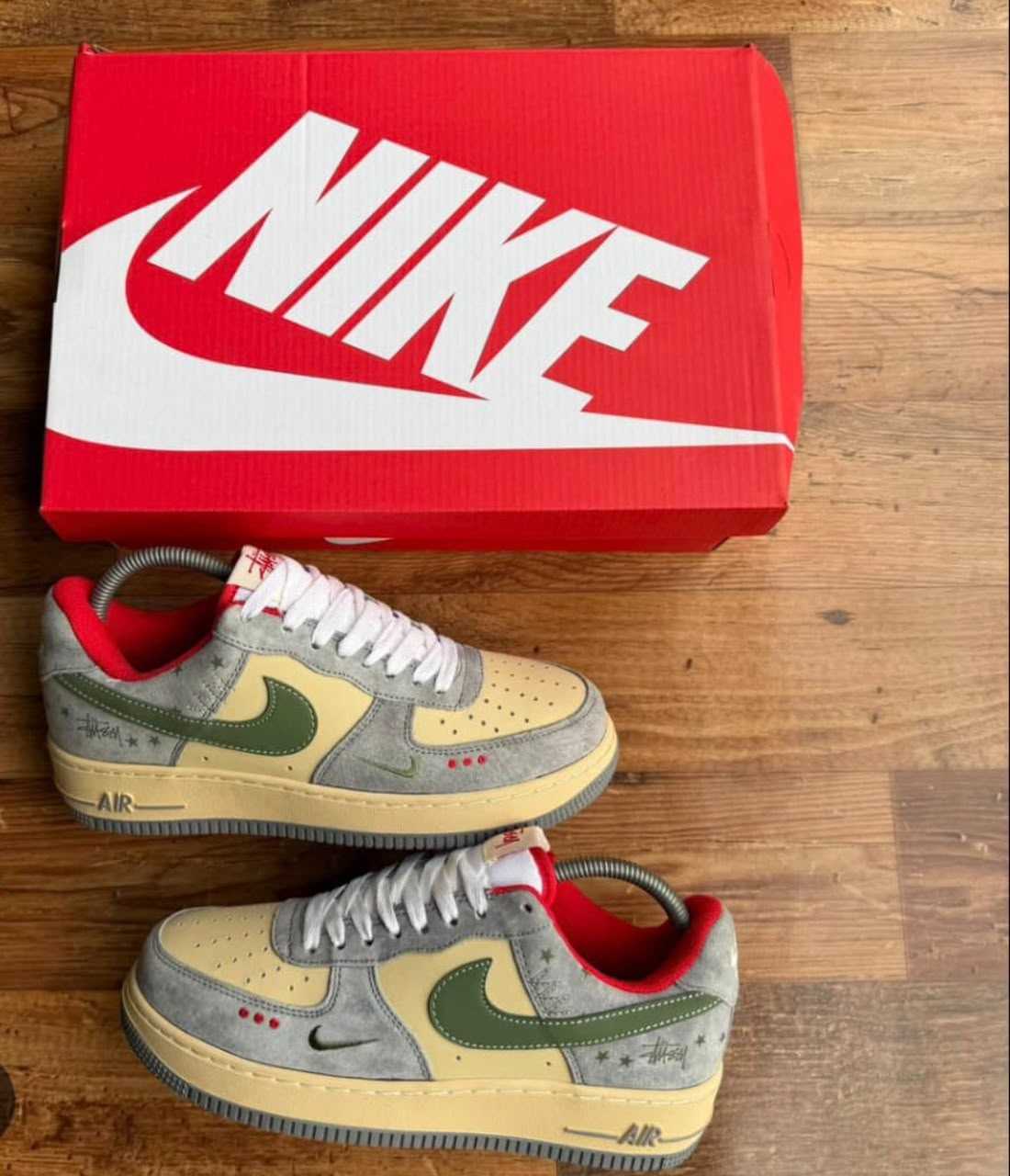 Nike Air Force 1 sneakers with cream and gray upper, green swoosh, red accents