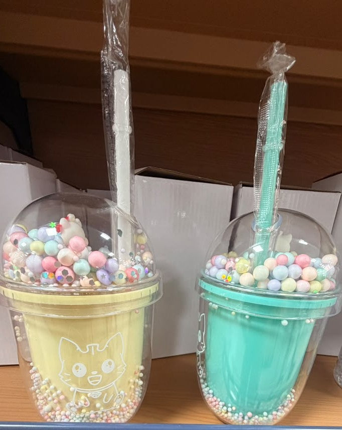 Set of two plastic party cups with straws, filled with colorful beads and candy.