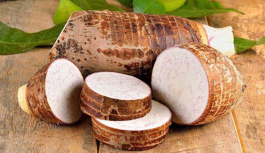 Brown root vegetable tubers with round slices, stacked on a wooden surface